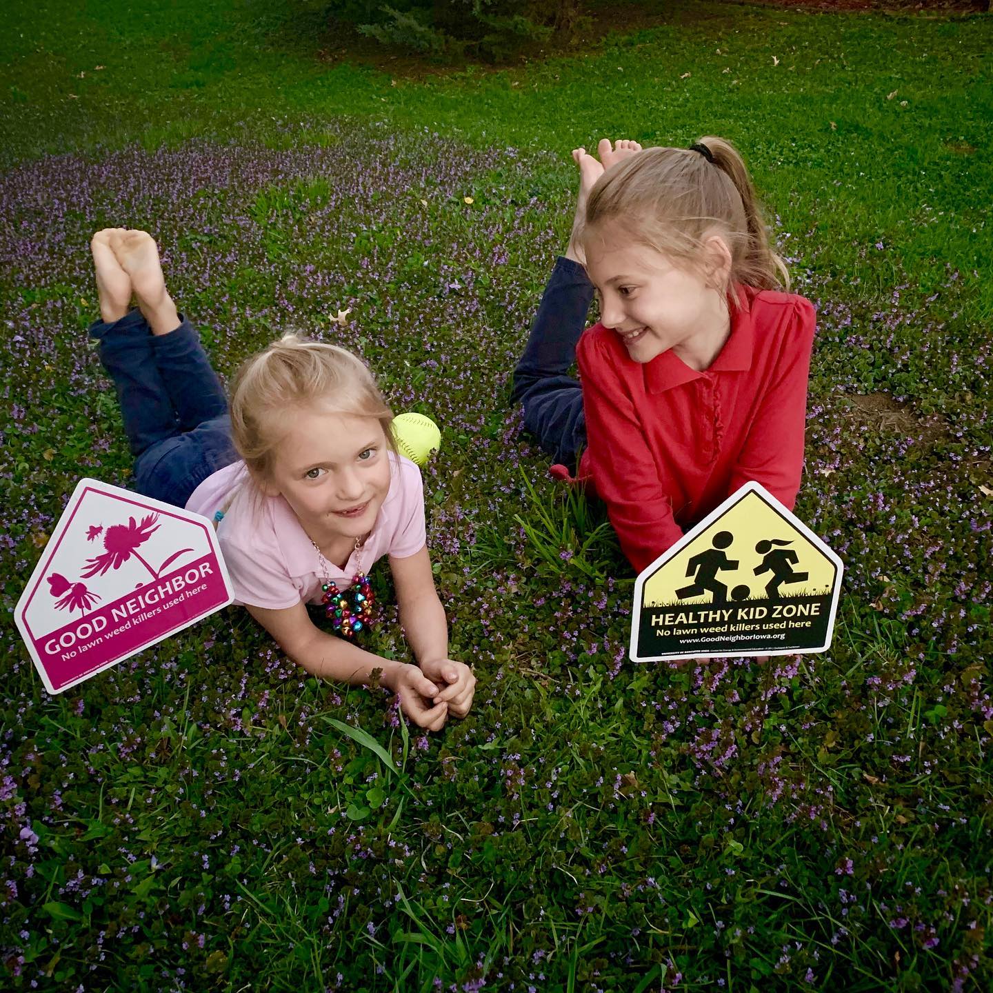 Two girls posing with Good Neighbor Iowa Lawn Signs
