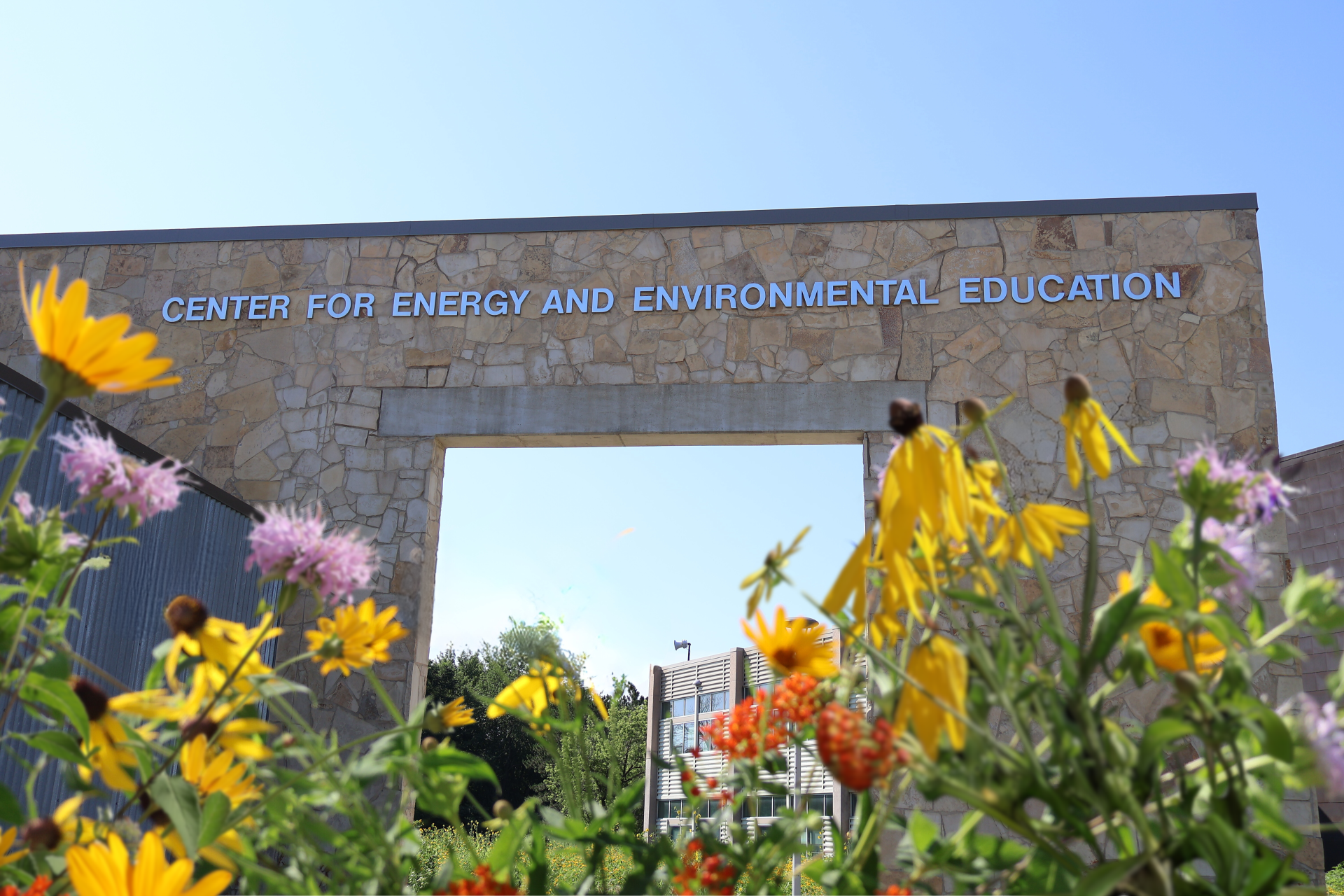 Stone archway in front of the CEEE building with flowers in the foreground