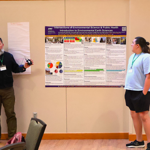 Two speakers in front of an informational poster